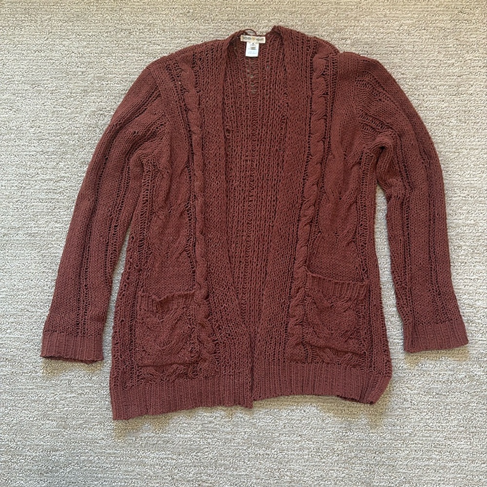 Woman’s dark orange/rust colored cardigan.